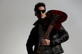 sexy cool guy with sunglasses wearing guitar on his shoulder and looking away Royalty Free Stock Photo