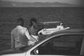 couple. Couple in love stand near silver car, sea on background. Couple arrived on vacation, honeymoon. Man and Royalty Free Stock Photo