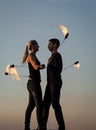 Sexy couple of fire dancers spin flaming poi on idyllic evening blue sky outdoors, motion Royalty Free Stock Photo