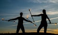 Sexy couple of fire performers manipulate flaming batons in evening shades on idyllic sky outdoors, nature Royalty Free Stock Photo