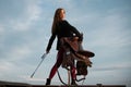 Sexy cowgirl hold saddle and whip. Equestrienne horsewoman. American cowboy style. Cowgirl woman in countryside