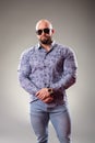 Sexy dressed muscular bodybuider with sunglasses on the gray background