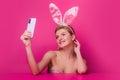 Sexy easter bunny woman with rabbit ears having call holding smart phone in hand shooting selfie on front camera Royalty Free Stock Photo