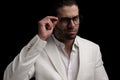sexy elegant man in white suit smiling and adjusting glasses Royalty Free Stock Photo