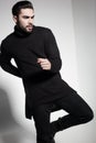 fashion man model in black sweater, jeans and boots posing dramatic