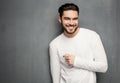 fashion man model in white sweater, jeans and boots smiling against wall