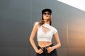 Sexy fashion model young woman in fashionable dark sunglasses in stylish youth cool clothes and american black cap poses near Royalty Free Stock Photo