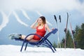 female skier on blue deck chair near skis at ski resort