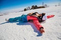 female snowboarder lying on her back on snow in winter in the mountains