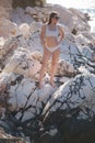 Sexy female stand on the rock in the sea. Attractive young woman in beautiful swimsuit by the sea Royalty Free Stock Photo