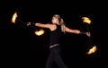 Sexy fire dancer manipulate burning batons during night performance in dark outdoors, party