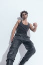 Sexy fit guy in leather pants and undershirt laying on a grey wall Royalty Free Stock Photo