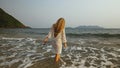 Woman in a white tunic on the beach, near the stormy sea. Blonde Royalty Free Stock Photo