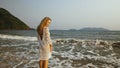 Woman in a white tunic on the beach, near the stormy sea. Blonde Royalty Free Stock Photo