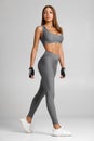 Sexy fitness woman. Beautiful athletic girl on the gray background