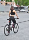 Sexy fitness. Young beautiful woman in black sport wear posing outdoor on the bicycle at the stadium Royalty Free Stock Photo