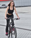 Sexy fitness. Young beautiful woman in black sport wear posing outdoor on the bicycle at the stadium Royalty Free Stock Photo