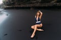 Sexy girl with big breasts in blue swimwear relaxing at beach with black sand. Royalty Free Stock Photo