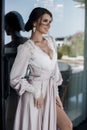 Beautiful young woman in a chic pink bathrobe spends time alone in an expensive hotel in the summer during the holidays Royalty Free Stock Photo