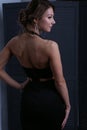 Sexy girl in evening black dress stands in front of the screen looking away