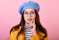 Beautiful lady in a stylish beret hat and a yellow raincoat with glasses shows dreams on a pink background Royalty Free Stock Photo