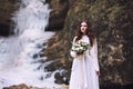 A girl is holding a wedding bouquet of flowers against the background of a glacier and mountains Royalty Free Stock Photo