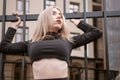 Sexy girl with long blonde heir near the fence. Portrait of young athletic woman in short black top Royalty Free Stock Photo