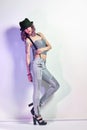 girl with purple hair and a tattoo on the body posing on grey background. Perfect woman in gray jeans and a t-shirt, bright Royalty Free Stock Photo