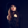 glamour female model posing in black shirt and elegant hat