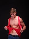 handsome young man tearing shirt off on a black background. Fitness and workout concept. Royalty Free Stock Photo