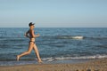 and happy beautiful woman in bikini running on the beach. In a cap with the inscription queen. Film effect. Royalty Free Stock Photo