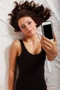 lazy girl lying with phone on bed in bedroom