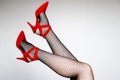 Female legs in black fishnet stockings and red shoes on high heels Royalty Free Stock Photo