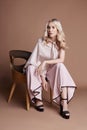 luxurious woman in a dress sitting on a chair. Autumn collection of women clothing. Fashion blonde in a long beautiful dress Royalty Free Stock Photo