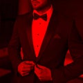 Sexy man in tuxedo and bow tie in red light Royalty Free Stock Photo