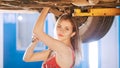 mechanic girl under the car with a spanner, looking in the camera Royalty Free Stock Photo