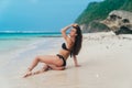 model in black swimsuit lying on white sandy beach. Girl sunbathes and rests on vacation at tropical island Royalty Free Stock Photo