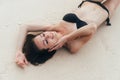 model in black swimsuit lying on white sandy beach. Girl sunbathes and rests on vacation at tropical island Royalty Free Stock Photo
