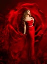 Sexy Model in Red Dress dancing over Fantasy Rose Background. Beauty Woman Art Portrait. Luxury Fashion Model in Evening Gown Royalty Free Stock Photo