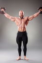 Sexy muscular bodybuider posing with weights on the gray background