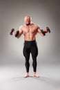 Sexy muscular bodybuider posing with weights on the gray background