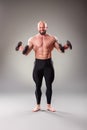 Sexy muscular bodybuider posing with weights on the gray background