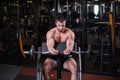 Sexy muscular man sitting on the bench and doind biceps exercise. Front view Royalty Free Stock Photo