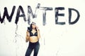 Sexy painter woman with wanted text on wall hold paintbrush