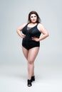 Sexy plus size fashion model in black one-piece swimsuit, fat woman in lingerie on gray background Royalty Free Stock Photo