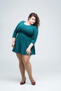 Sexy plus size fashion model in green dress, fat woman on gray background, body positive concept