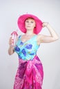 Sexy plus size girl in a blue swimsuit, fuchsia hat with brim and in a trendy bright pareo stands on a white background in the Stu Royalty Free Stock Photo