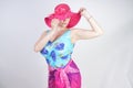 Sexy plus size girl in a blue swimsuit, fuchsia hat with brim and in a trendy bright pareo stands on a white background in the Stu Royalty Free Stock Photo