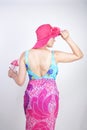 Sexy plus size girl in a blue swimsuit, fuchsia hat with brim and in a trendy bright pareo stands on a white background in the Stu Royalty Free Stock Photo