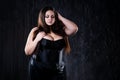 Sexy plus size model in black corset, fat woman with big natural breasts on dark background, body positive concept